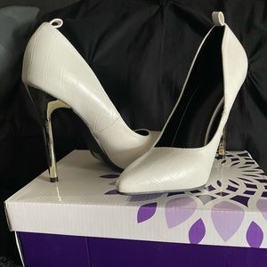 Gator style white pumps with a gold heel.